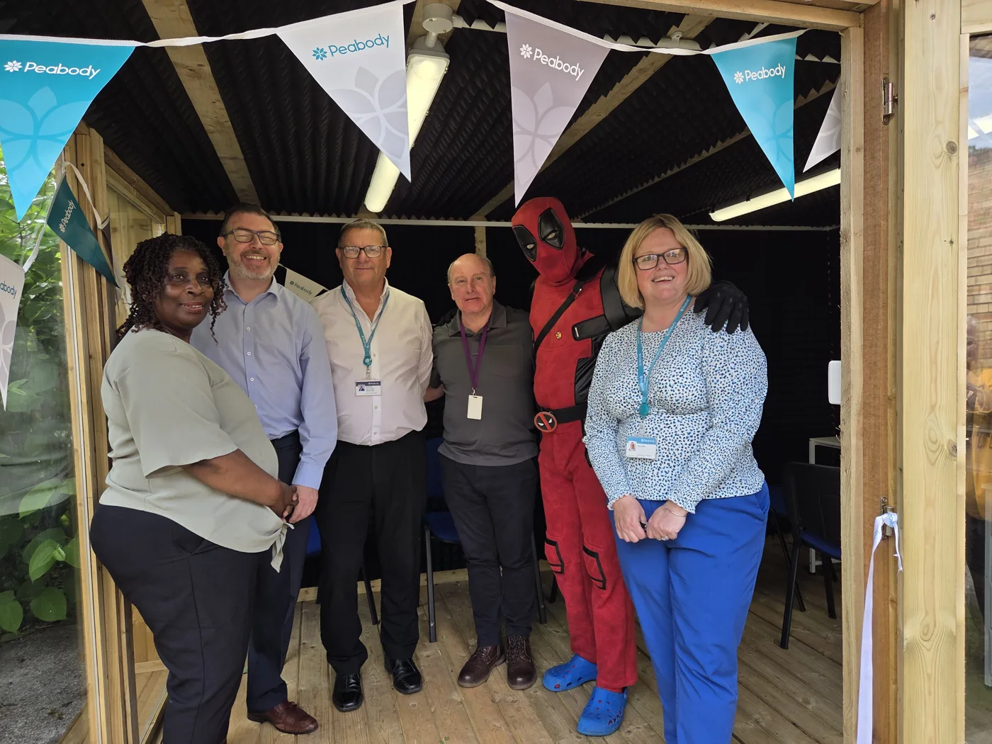 Visitors at the door of the Ameina Centre's music studio, under Peabody bunting, with a guest dressed as Deadpool
