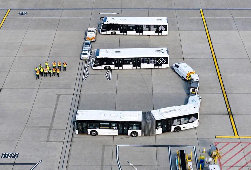 Airside buses and vehicles lined up in the shape of a 5 on the apron at London Luton Airport, with staff alongside, to mark the fifth year.