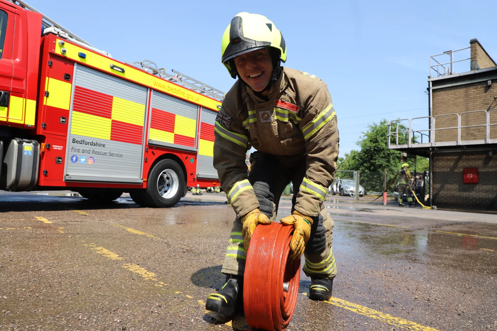 A Bedfordshire Fire and Rescue Service firefighter rolls a hose beside a fire engine. The service used the picture to launch its consultation.